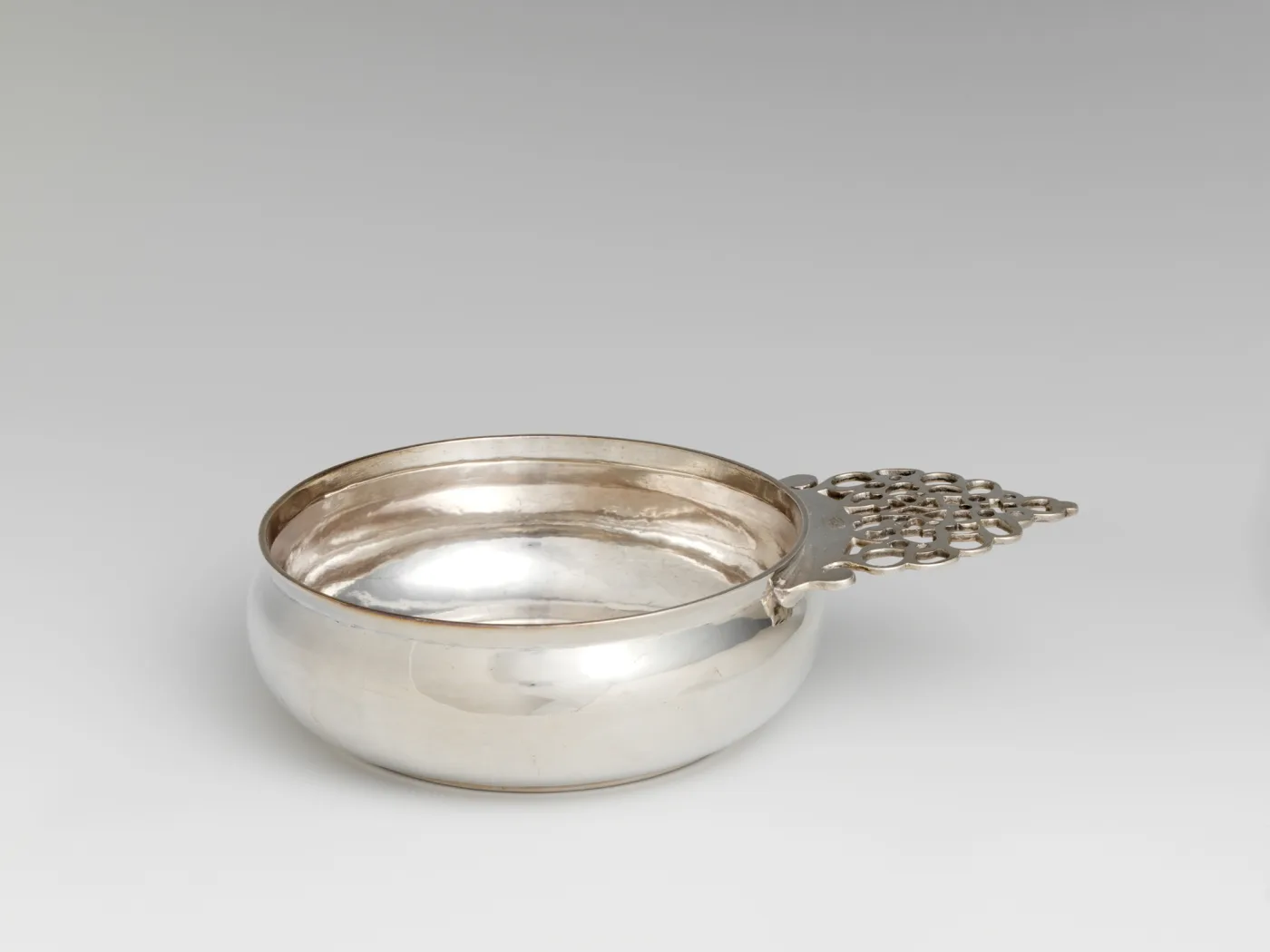 Silver porringer by Peter Van Dyck of New York with a broad handle pierced with rows of small circles across its whole area