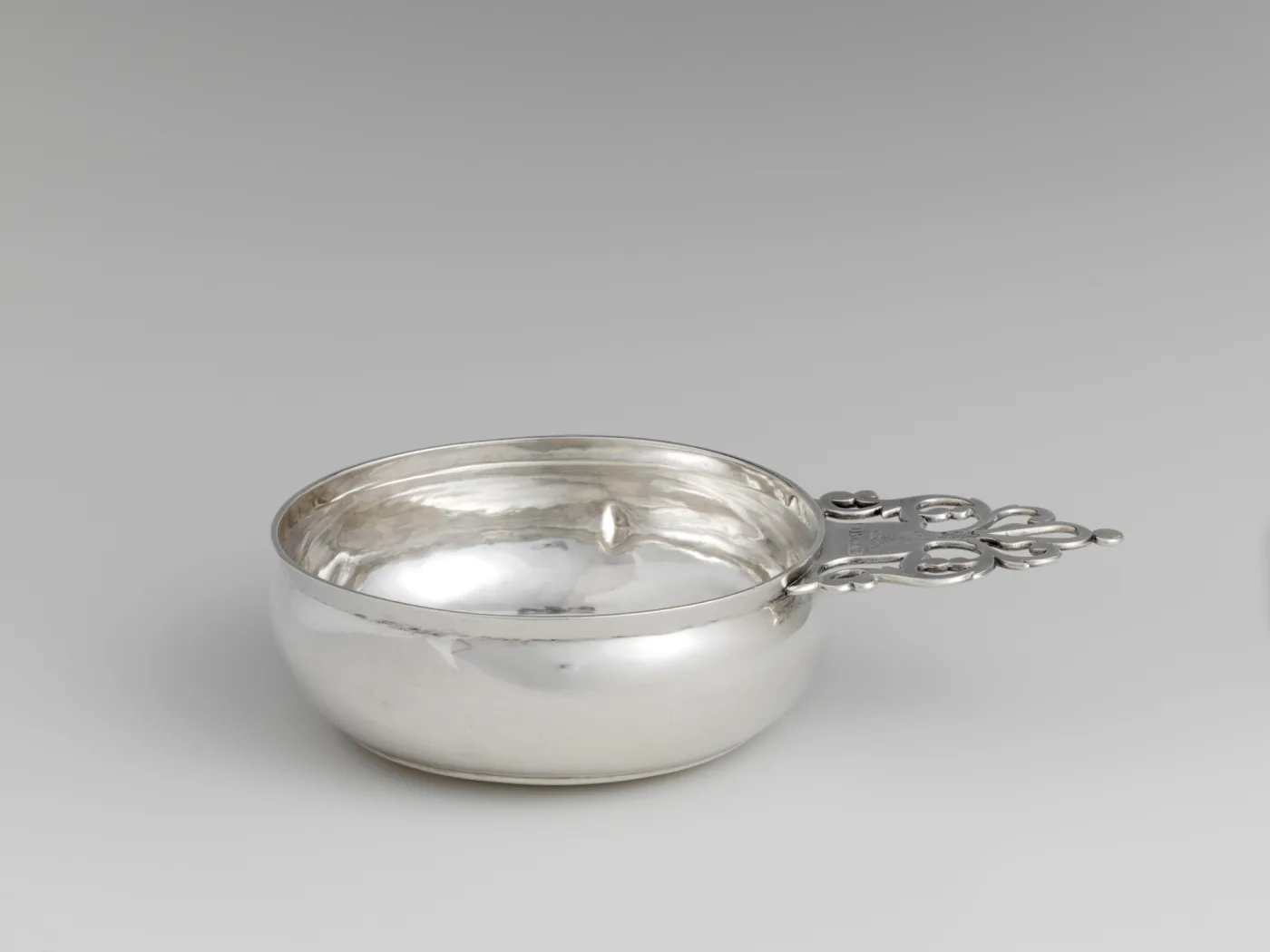 Silver porringer by Benjamin Burt of Boston dated 1763 with a keyhole handle and the maker's mark struck on the handle shank