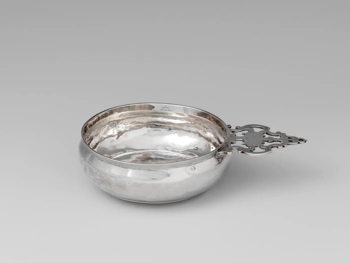 Silver porringer by William Cowell Sr. of Boston with a scrolled pierced handle, a small WC mark struck on the outside of the bowl and the initials A E B over 1741 engraved on the handle
