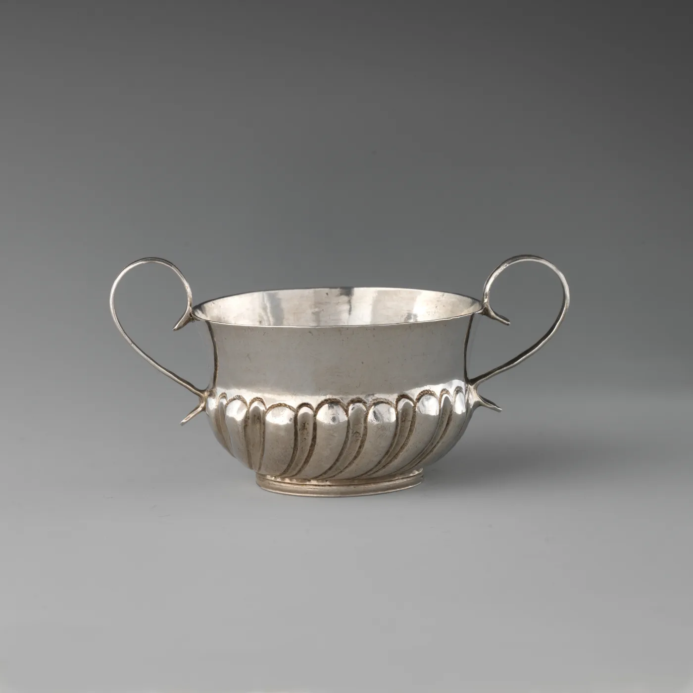 Miniature two-handled London porringer of 1690 to 91 with gadrooning around the lower body and two looped wire handles