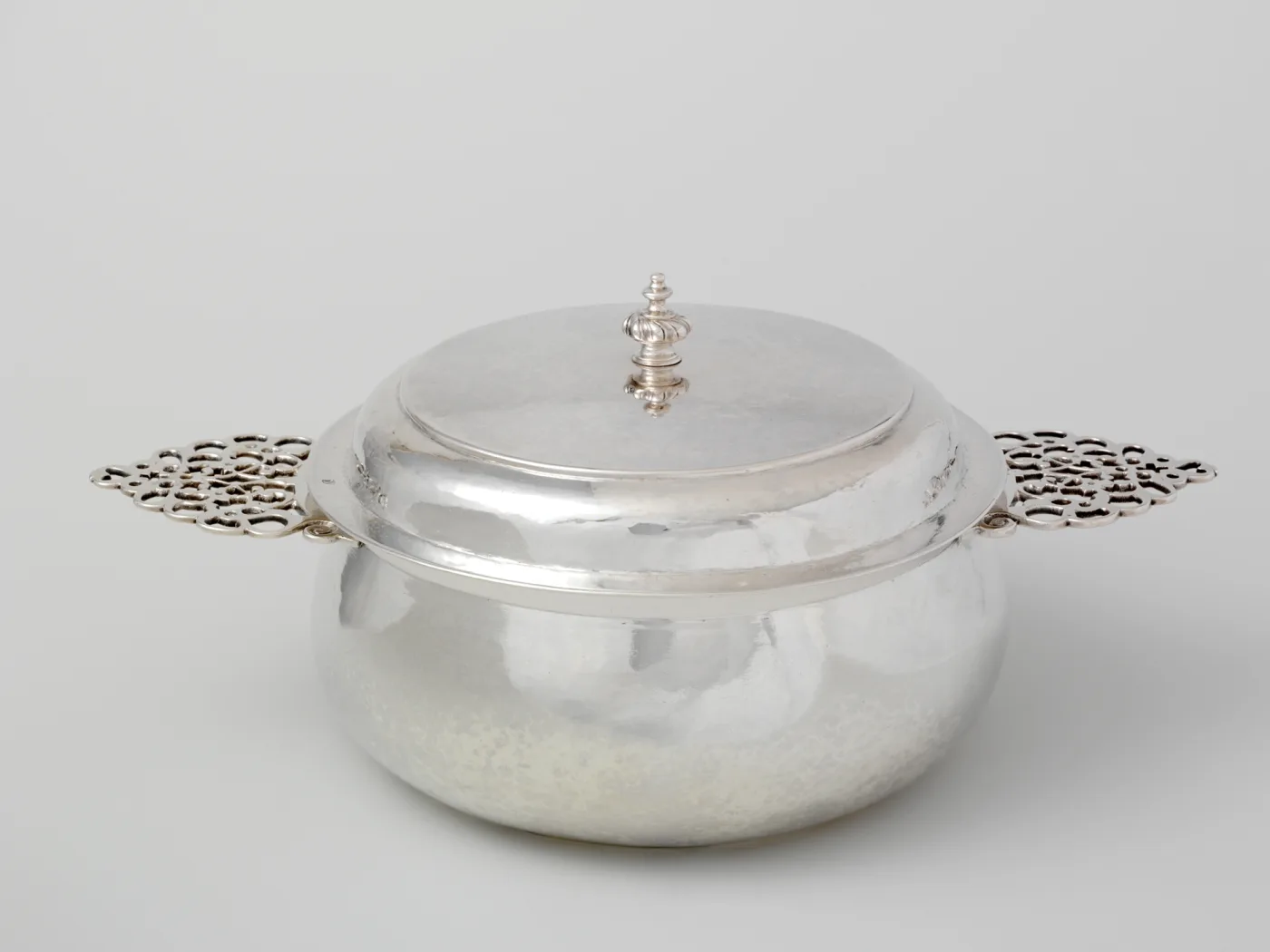 American covered porringer of 1700 to 20 with two flat pierced handles and a domed cover with a turned finial