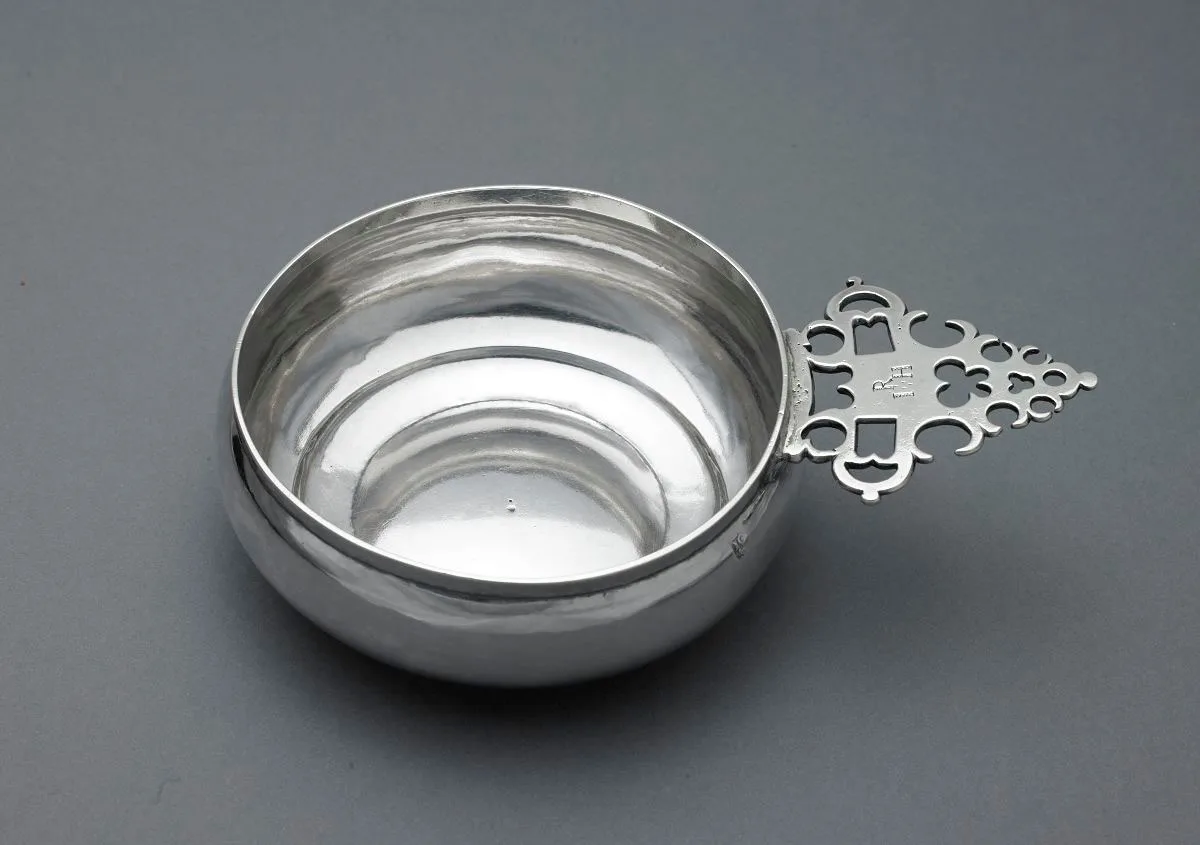 Silver porringer by John Coney of Boston of about 1710 photographed from above showing concentric planishing rings inside the bowl and a geometric handle with square voids