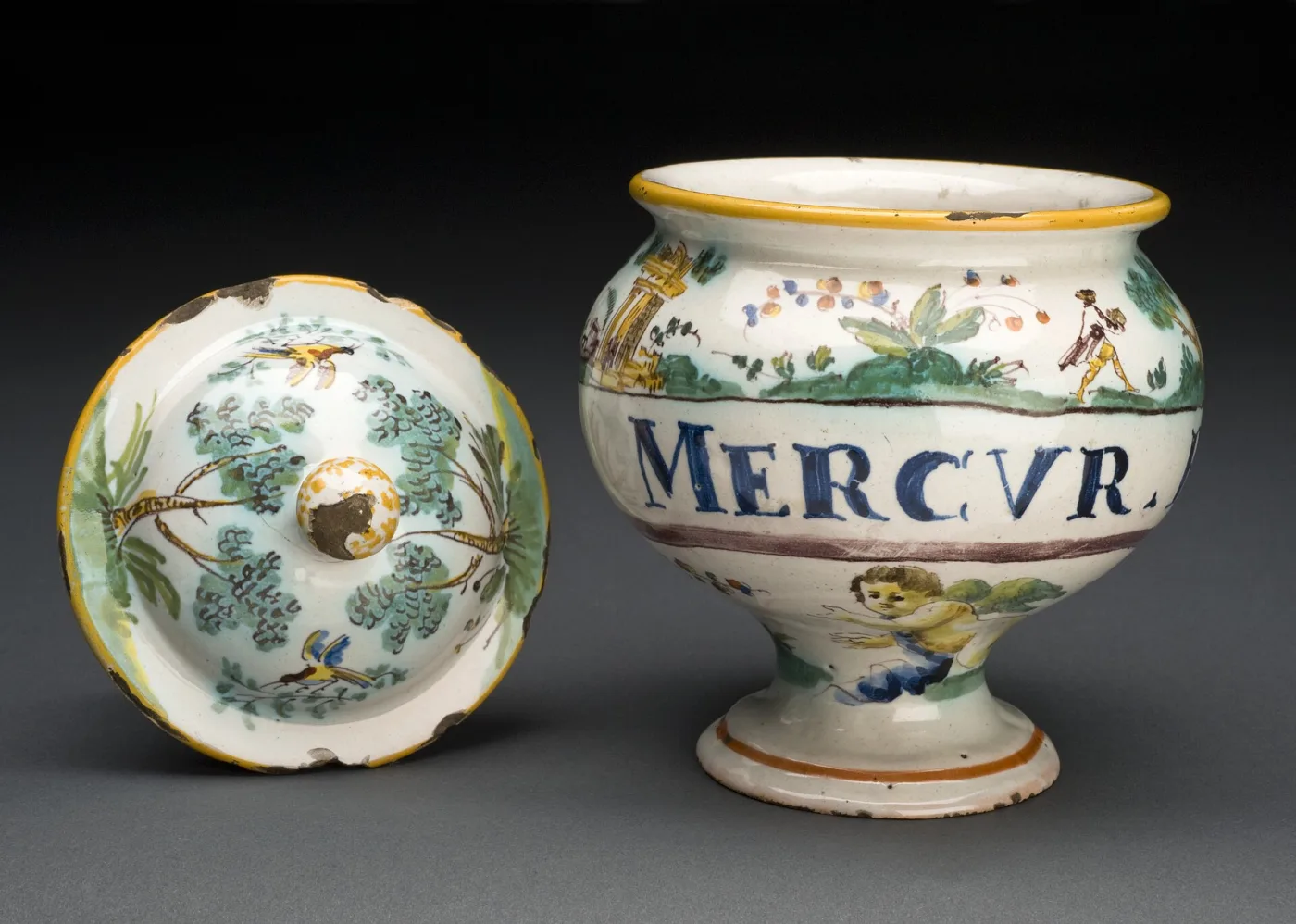 Italian footed drug jar lettered MERCVR standing beside its detached domed cover, the cover lying face up with painted birds and foliage and the glaze knocked off its knop and rim