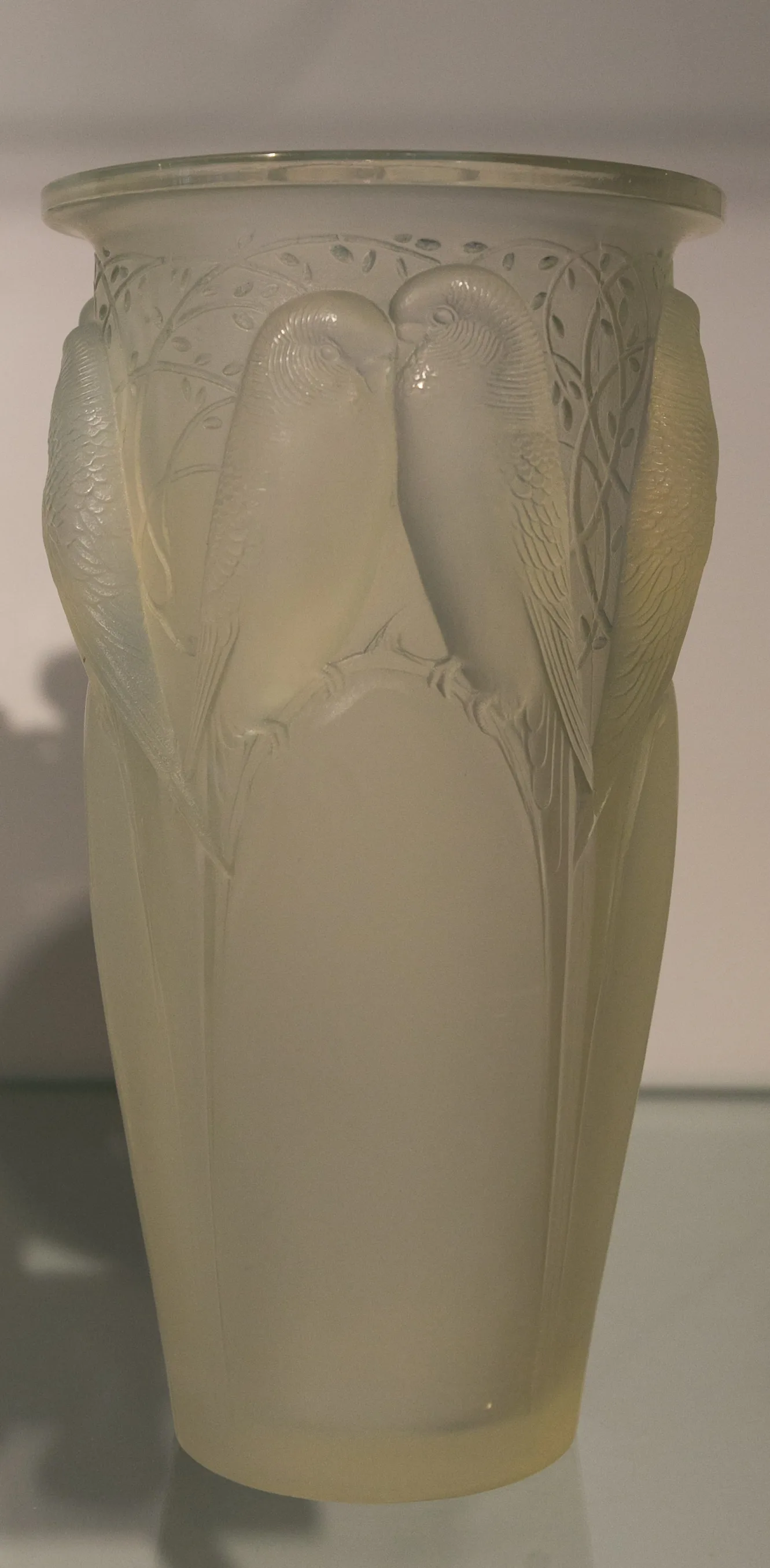 Tall frosted glass vase moulded in relief with pairs of budgerigars perched among leafy branches