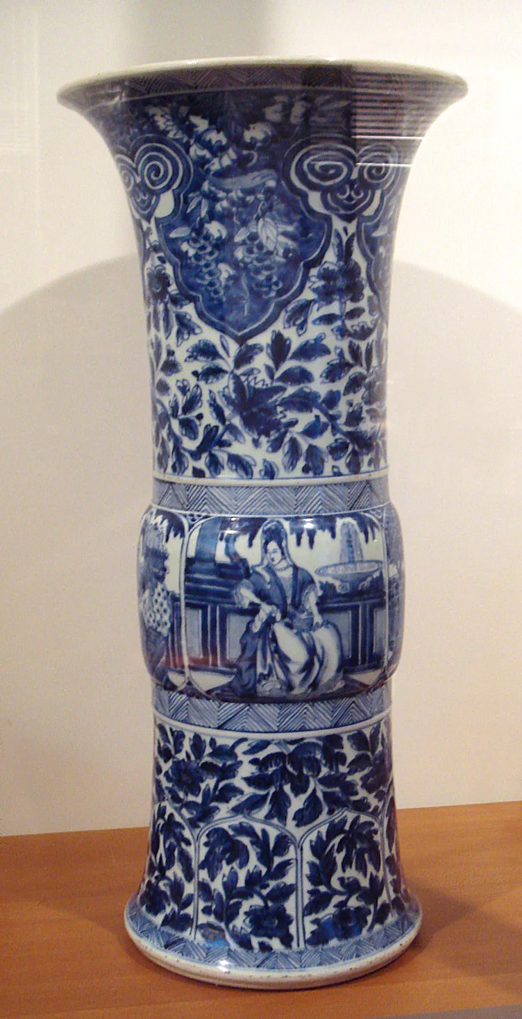 Tall blue and white beaker vase with a flaring rim, painted in horizontal registers with figures in European dress among scrollwork borders