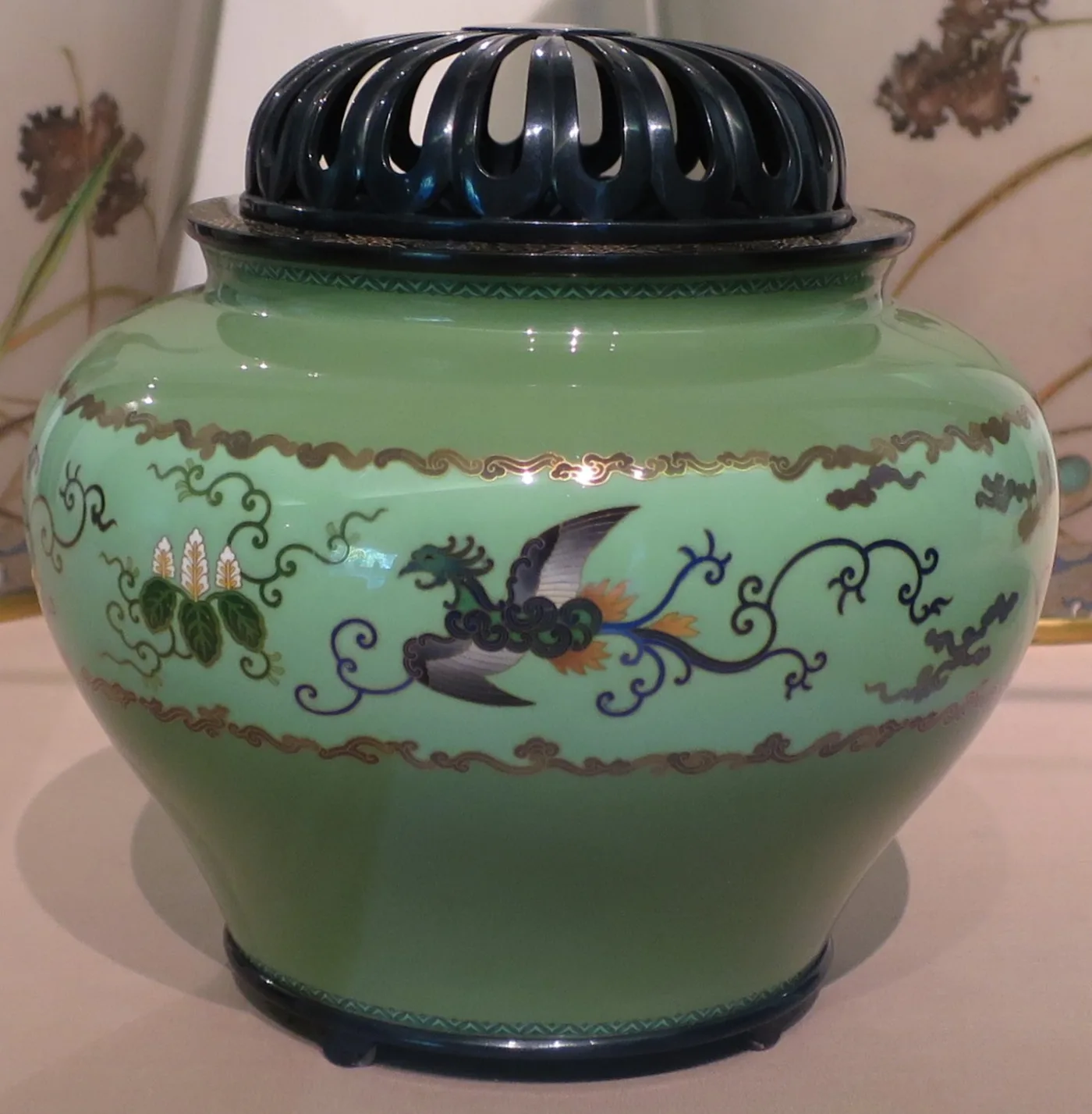 Rounded jar-shaped incense burner in pale green enamel decorated with birds and trailing vines in fine wirework, closed by a dark pierced domed cover