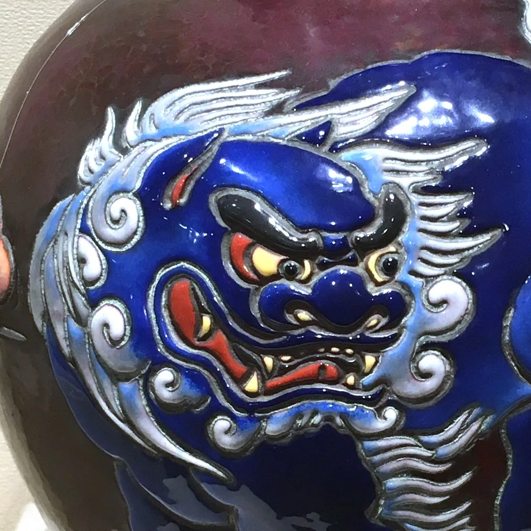 Deep blue vase with a stylised lion-dog whose mane and body stand out in raised relief, outlined by silver contours rather than flat wires