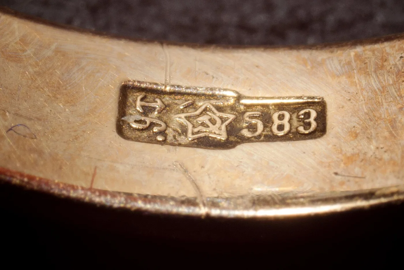 Close-up of a gold band bearing a small struck oval containing a five-pointed star with a hammer and sickle, followed by the number 583