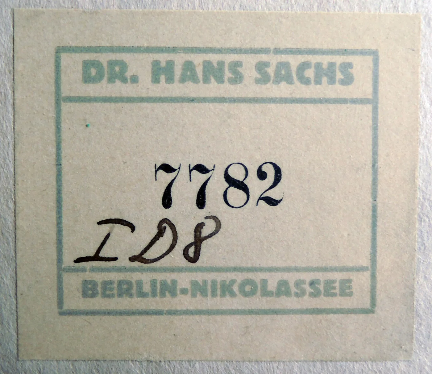 Small printed collection label with a green border reading Dr. Hans Sachs, Berlin-Nikolassee, with the number 7782 written on it by hand