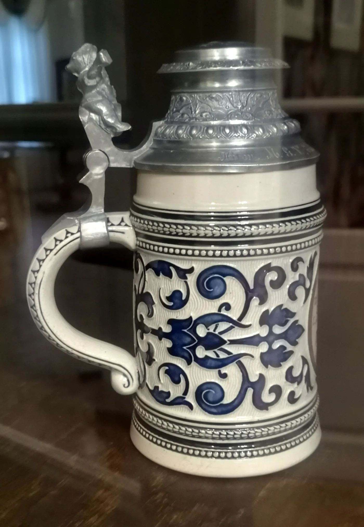 Blue and white stein with a pewter lid and a cast figural thumblift above the handle