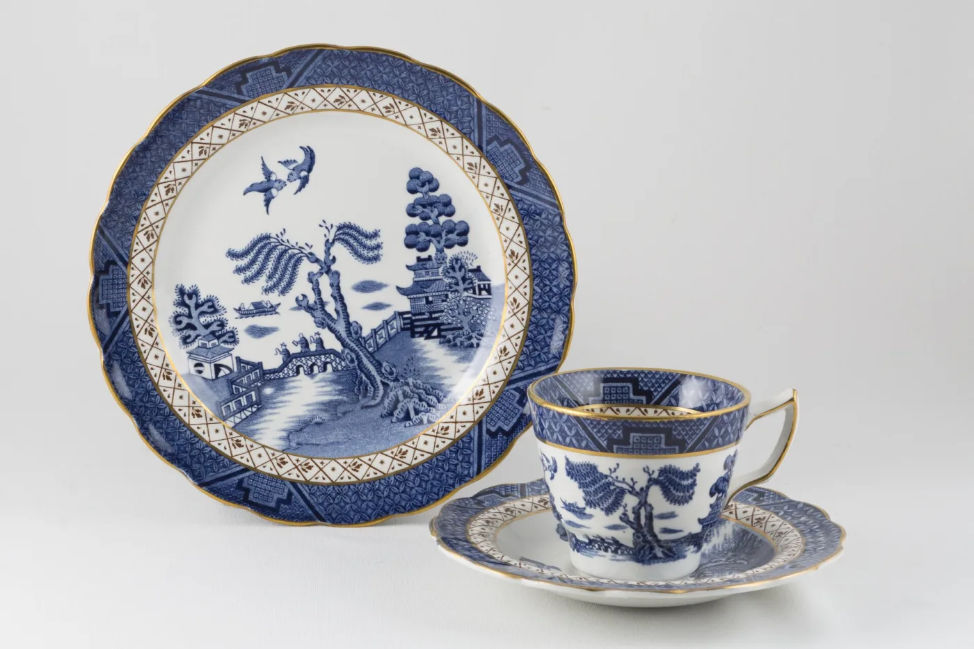 Willow plate, teacup and saucer with a deep cobalt border, a gold-and-white diaper band and gilded rims