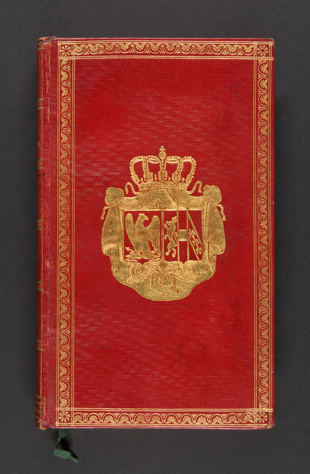 Bright red leather book cover tooled in gold, with a wide decorative border and a large gilt coat of arms with a crown at its centre