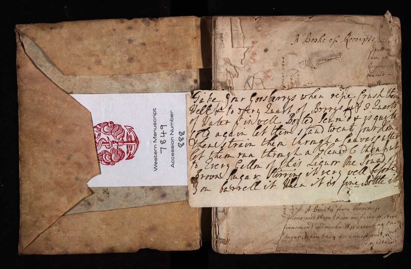 Small handwritten book lying open, its limp parchment cover extending into a wide flap that folds over the fore-edge, the pages covered in close brown ink handwriting