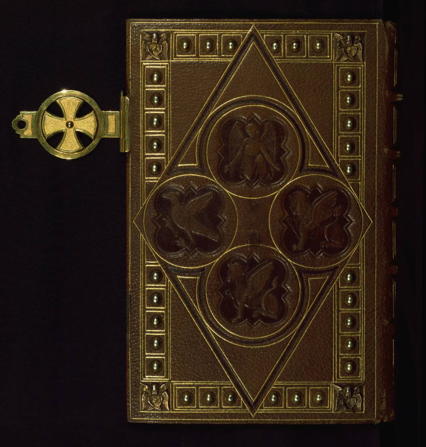 Brown morocco book cover with gilt silver studs set along the edges, silver cherub bosses at the corners, blind-stamped panels showing the symbols of the Evangelists, and a metal clasp