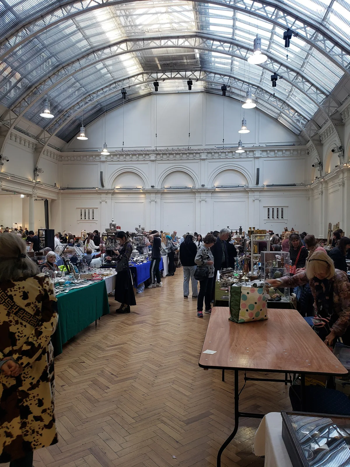 Dealers and visitors at trestle tables under the high arched glass roof of a London exhibition hall