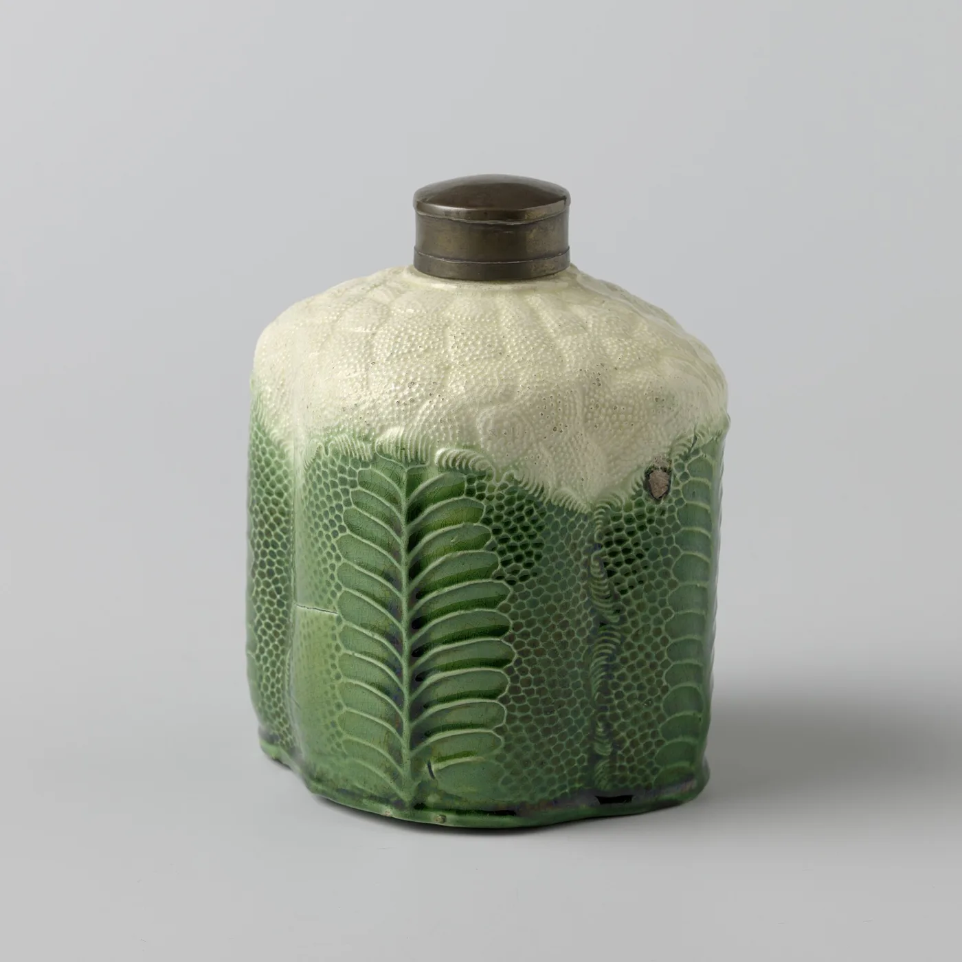 Cylindrical lobed tea caddy with green moulded leaves below, a stippled cream cauliflower top, and a metal screw cap