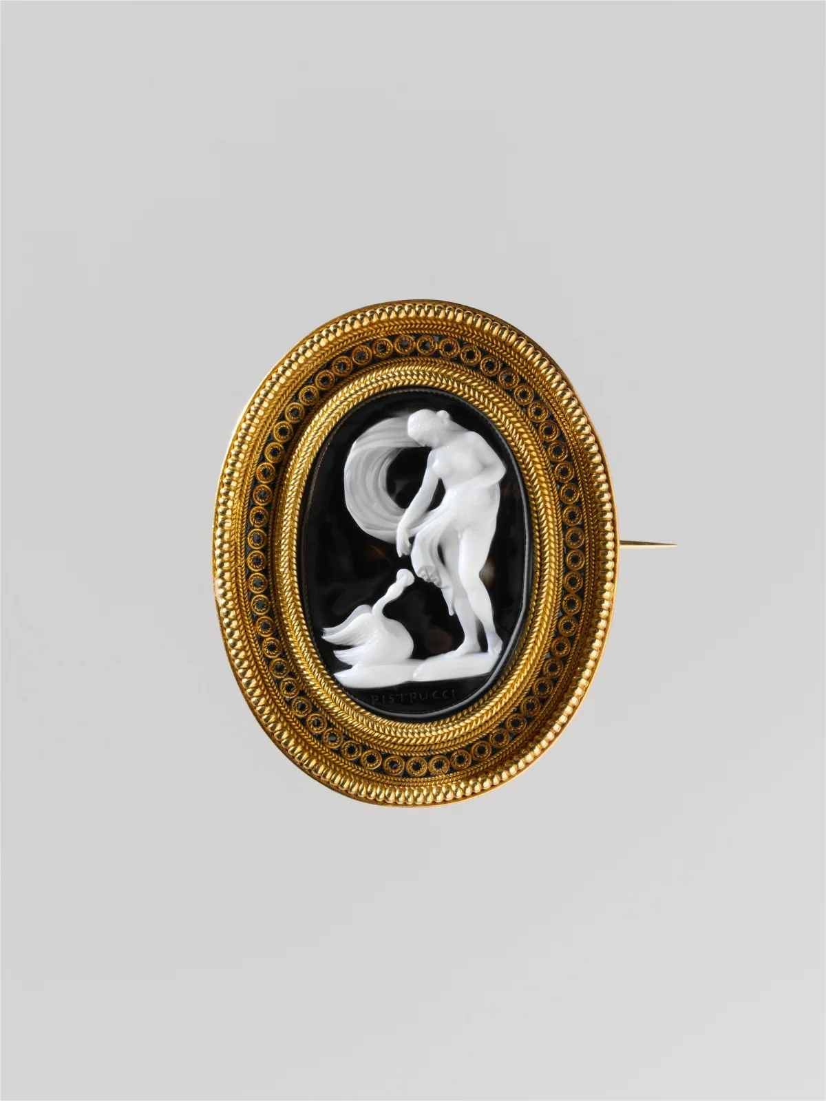 Oval brooch in an Etruscan-revival granulated gold mount, set with a cameo of a nude nymph bending towards a swan carved in brilliant white against a jet-black ground, signed in the ground below, with a long pin projecting at the right