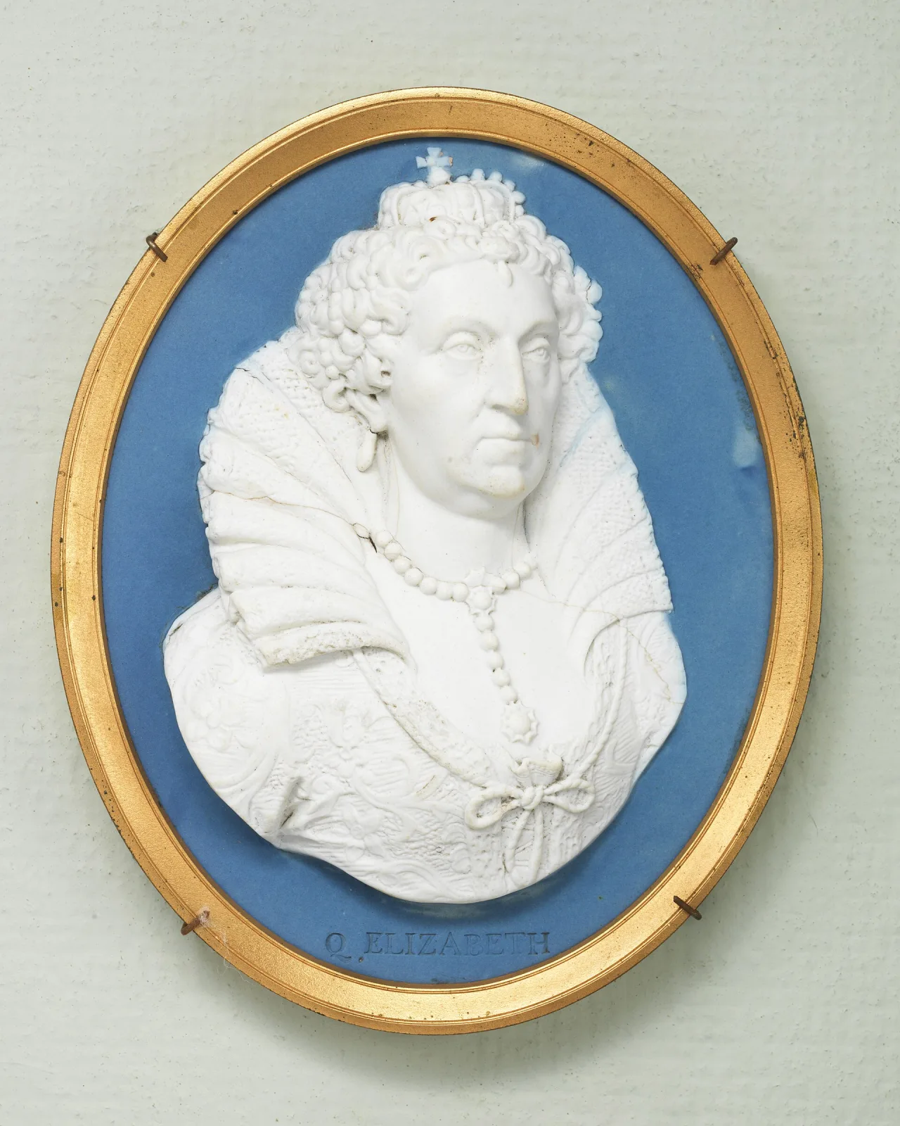 Oval jasperware medallion in a gilt frame, with a white bisque relief bust of Queen Elizabeth I in a ruff and jewelled headdress applied to a flat pale blue ground, the words Q ELIZABETH moulded below, and fine hairline cracks running through the white relief