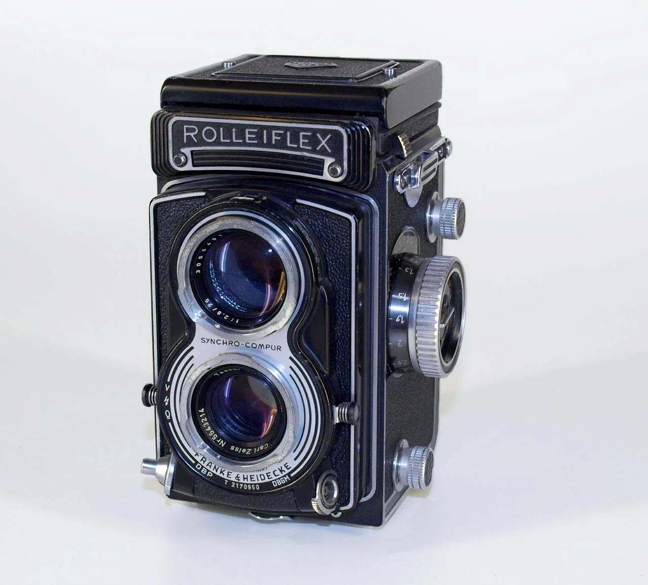 Twin lens reflex camera seen from the front, with two matched lenses mounted one above the other in a squared body, focusing knob at the side and a hooded viewfinder on top