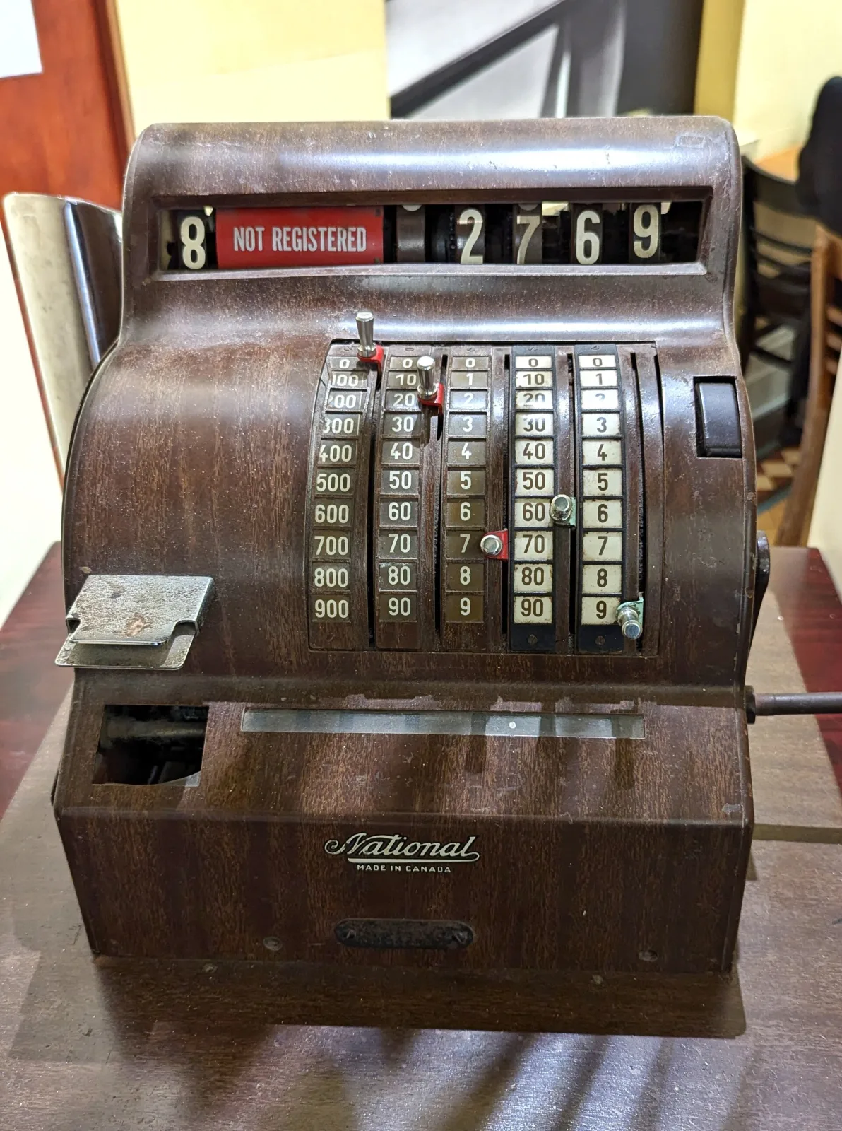 Wooden-cased National cash register with a plain glazed top sign reading not registered, a flat keyboard and a simple drawer