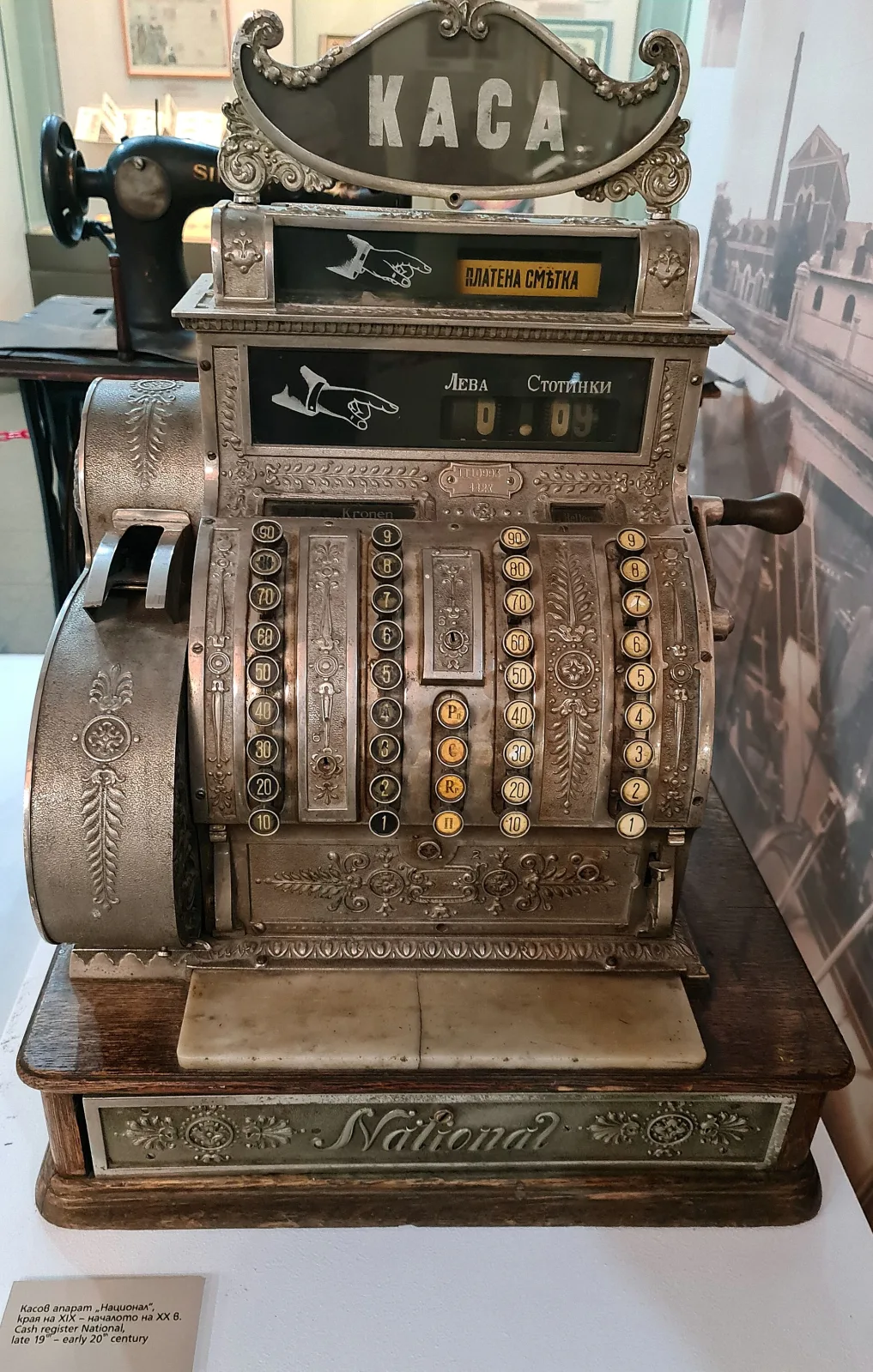 Ornate cast-metal cash register with a scrolled top sign, banks of round keys in several colours, a side crank and a heavy moulded drawer front
