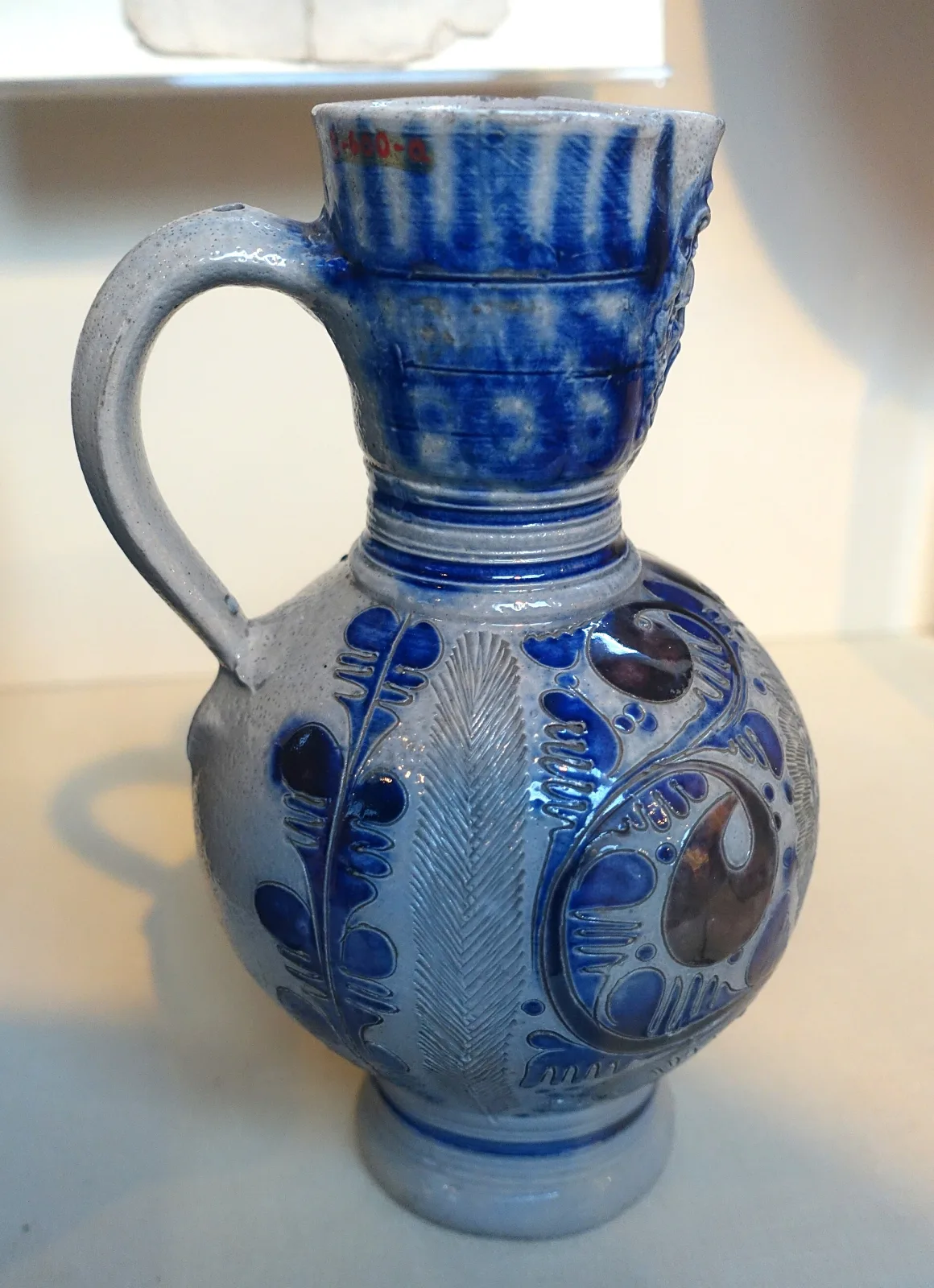 Grey salt-glazed stoneware jug with cobalt blue decoration, its body carrying applied moulded medallions and incised bands