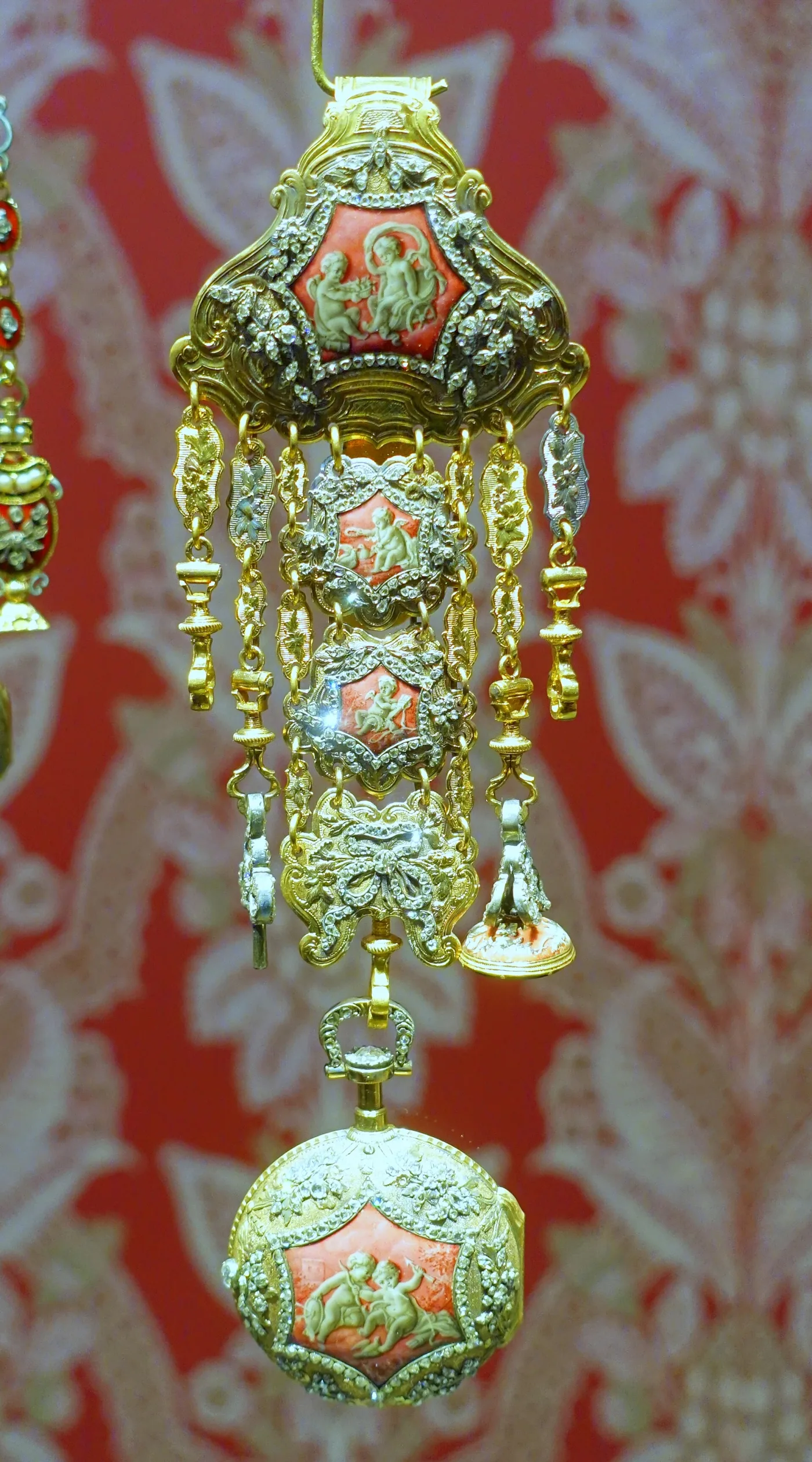 Gold rococo chatelaine set with diamonds and painted enamel figure panels, with a matching pocket watch hanging below it