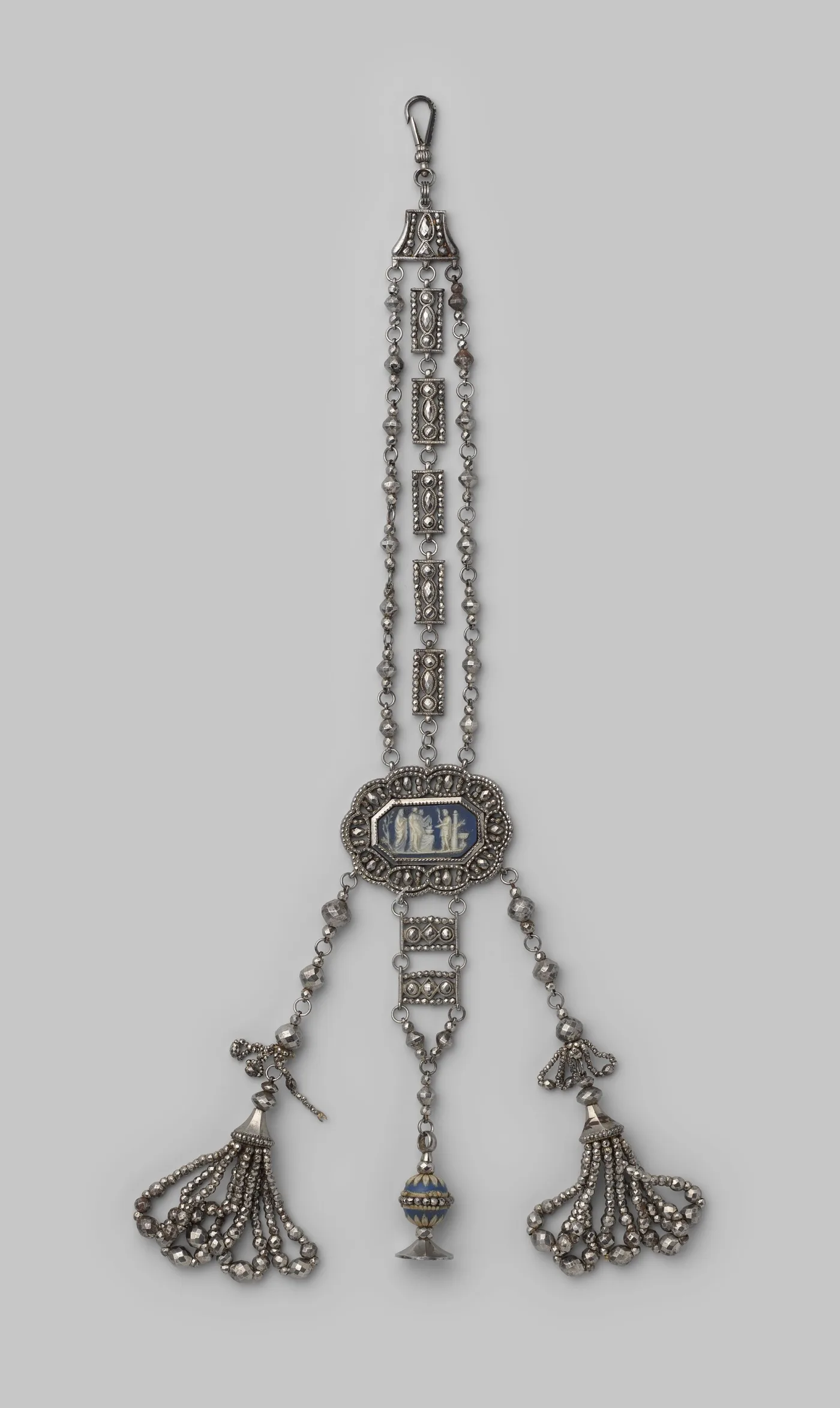 Cut steel chatelaine of three chains built from faceted steel beads and pierced steel rectangles, hung with a blue and white Wedgwood stoneware medallion