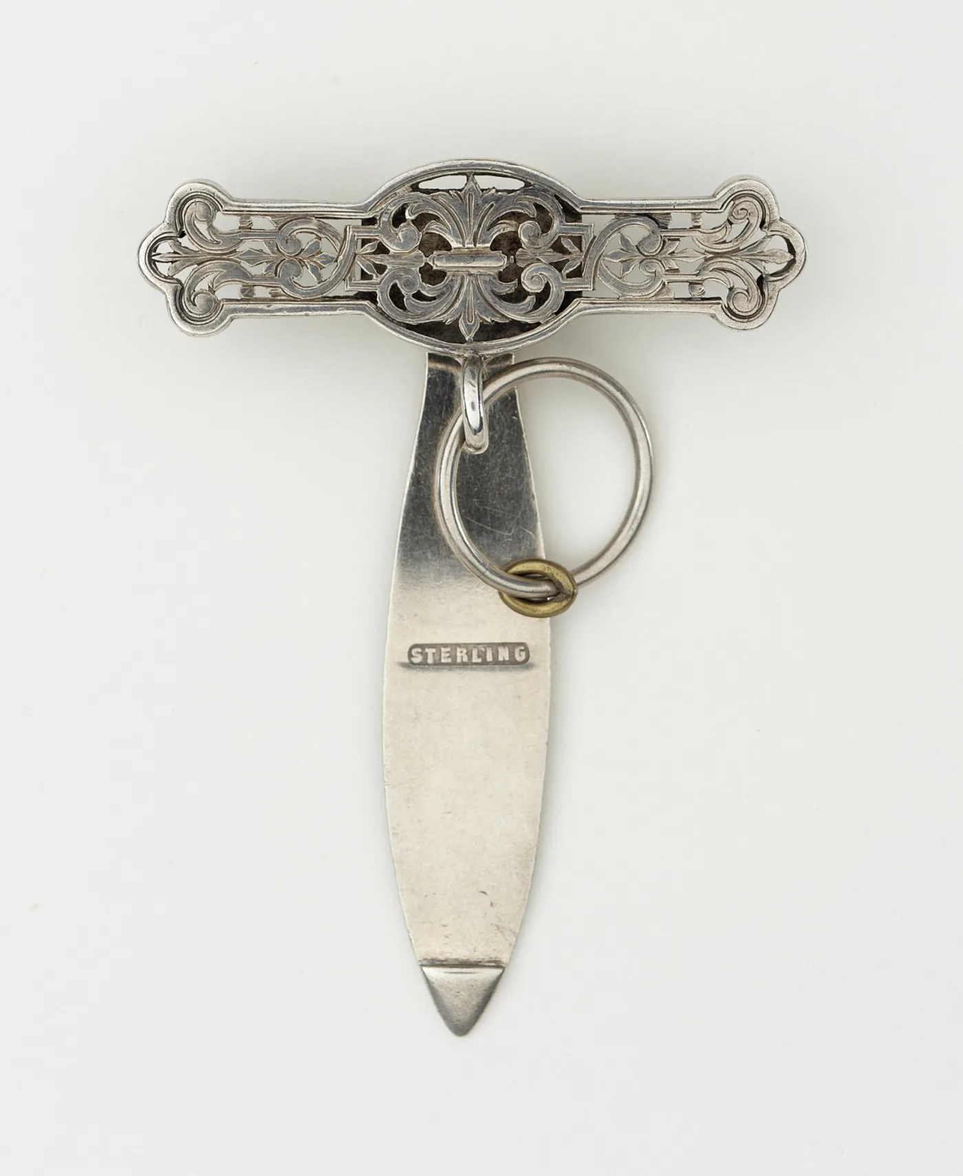 Reverse of a pierced silver chatelaine clip, showing the flat tongue that slides behind a belt struck with the single word STERLING