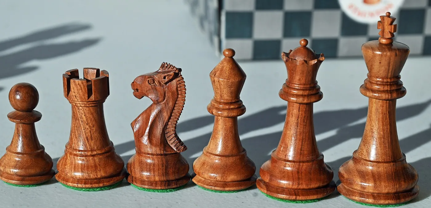 Row of turned rosewood chess pieces in Staunton pattern, from pawn through rook, knight, bishop, queen and king