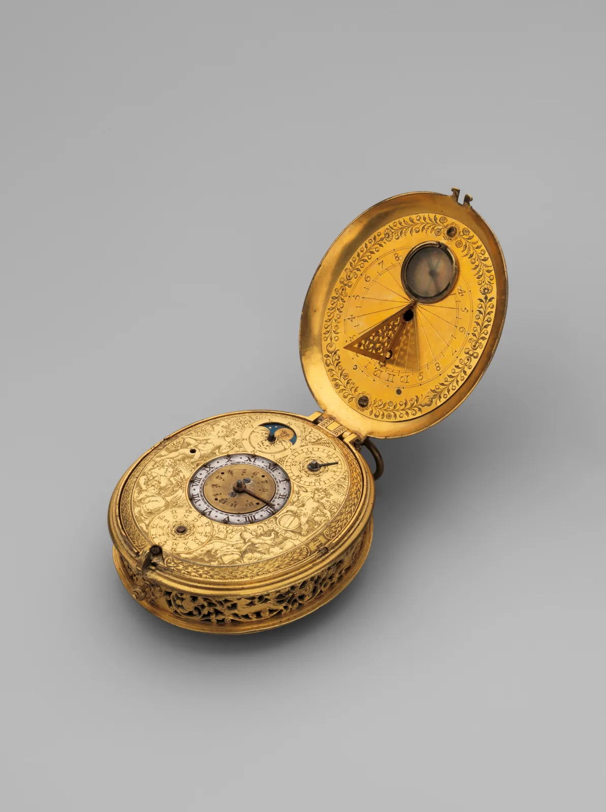 Small gilt watch with a pierced and engraved case lying open, the inside of its lid engraved as a sundial with a folding gnomon and a tiny compass set at the centre