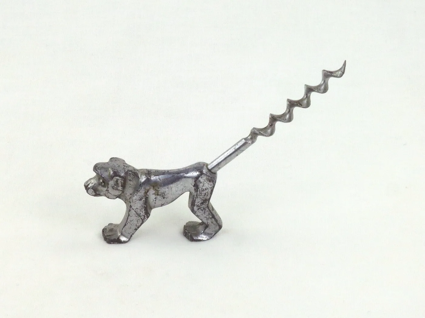 Cast metal corkscrew in the form of a standing dog, its tail drawn out into a long twisted worm
