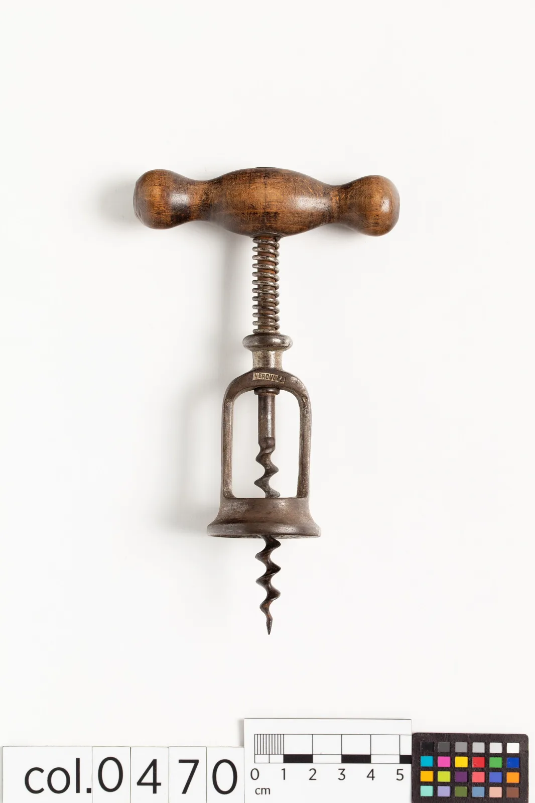 Frame corkscrew photographed flat against white with a centimetre ruler and a colour reference chart laid beside it, labelled col.0470