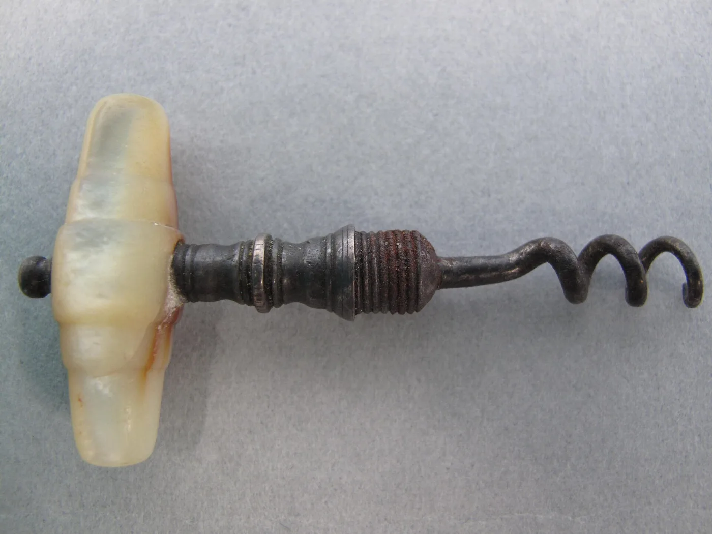 Corkscrew with a lobed mother-of-pearl crossbar handle, a turned steel shank with a ringed collar, and a wide open spiral worm