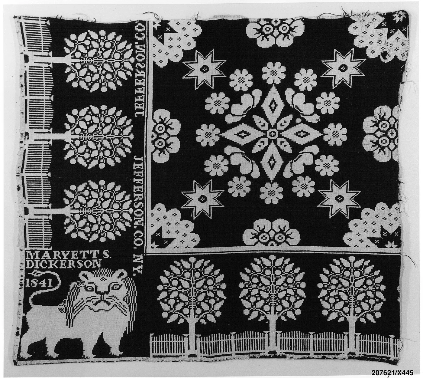 Corner of a black and white coverlet showing a large woven lion, a block lettered MARYETT S. DICKERSON 1841, the words JEFFERSON CO. N.Y. running vertically down the side border, and a bottom border of trees behind a fence