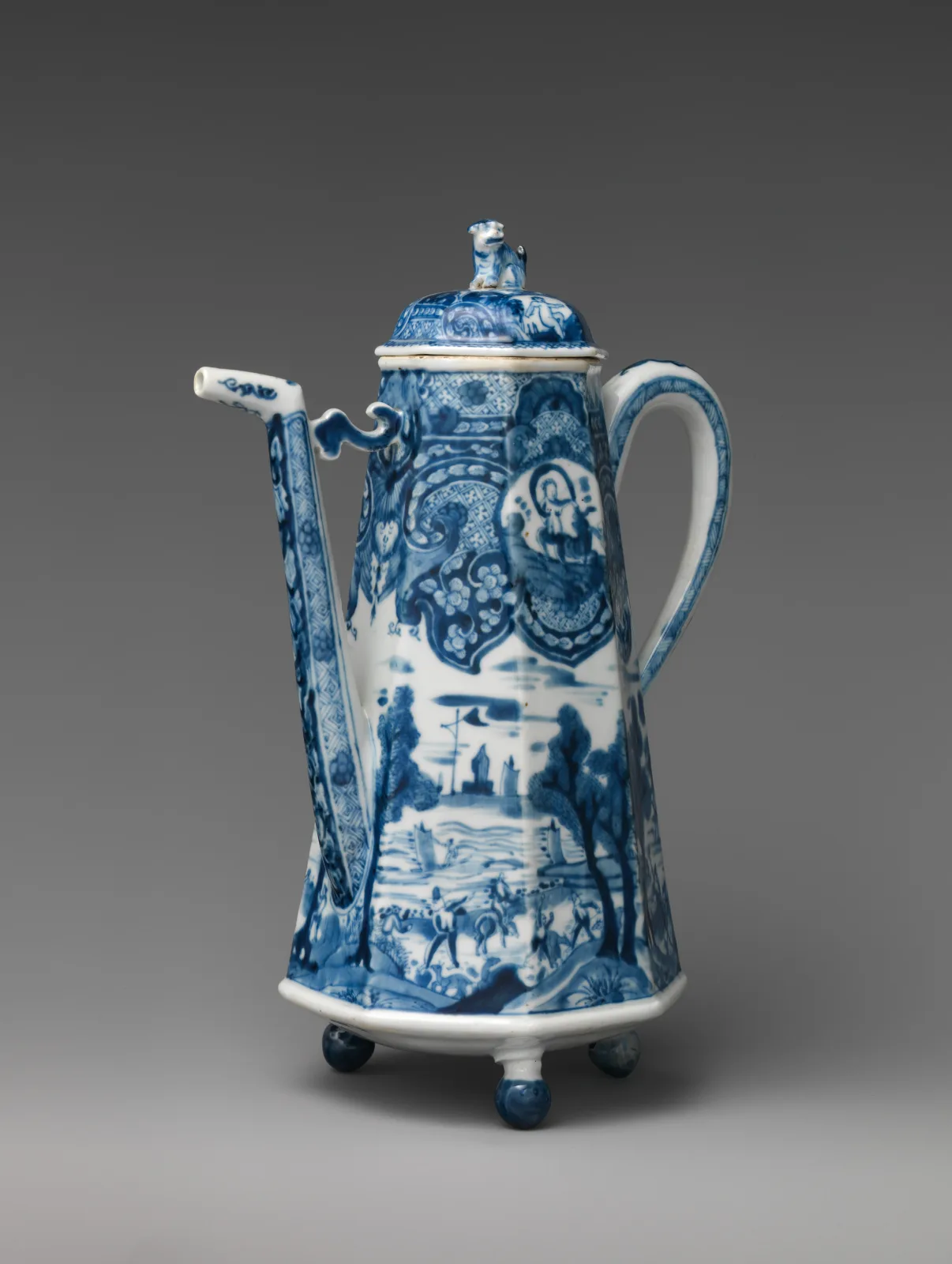Tall tapering blue and white coffeepot with a domed hinged cover, a long straight spout supported by a strut, a scrolled handle and a painted landscape panel, standing on three small feet