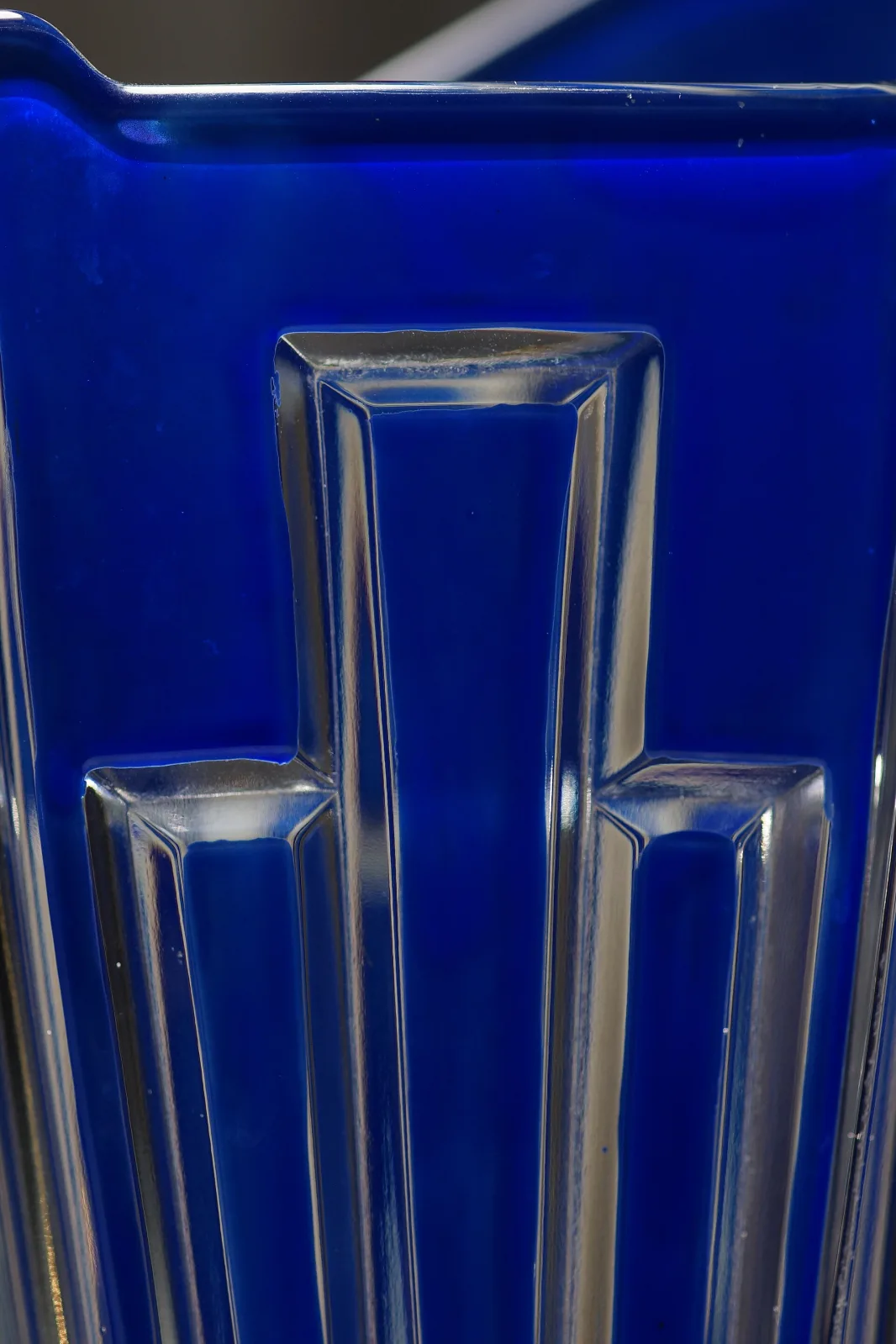Close view of a cobalt blue glass pitcher with tall stepped vertical ribs catching the light