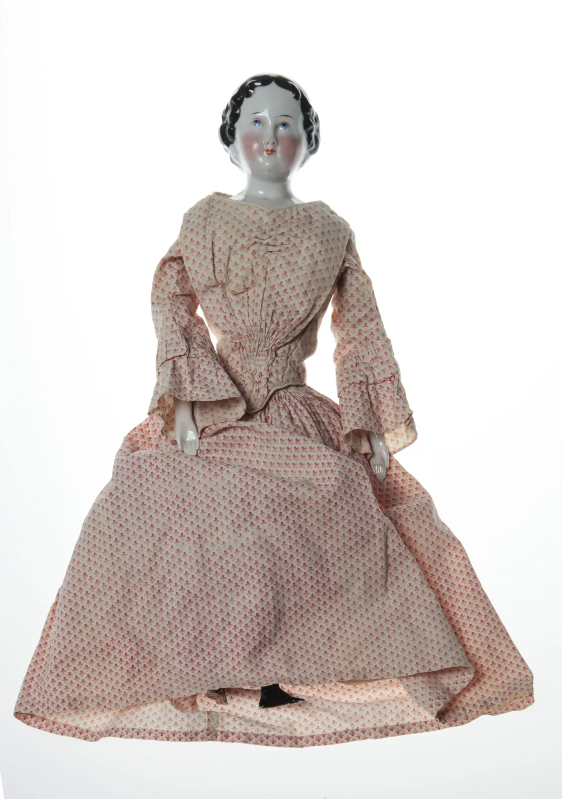 Doll with a glossy white china head, moulded black hair and painted features, on a stuffed cloth body, dressed in a long pink and white printed cotton gown