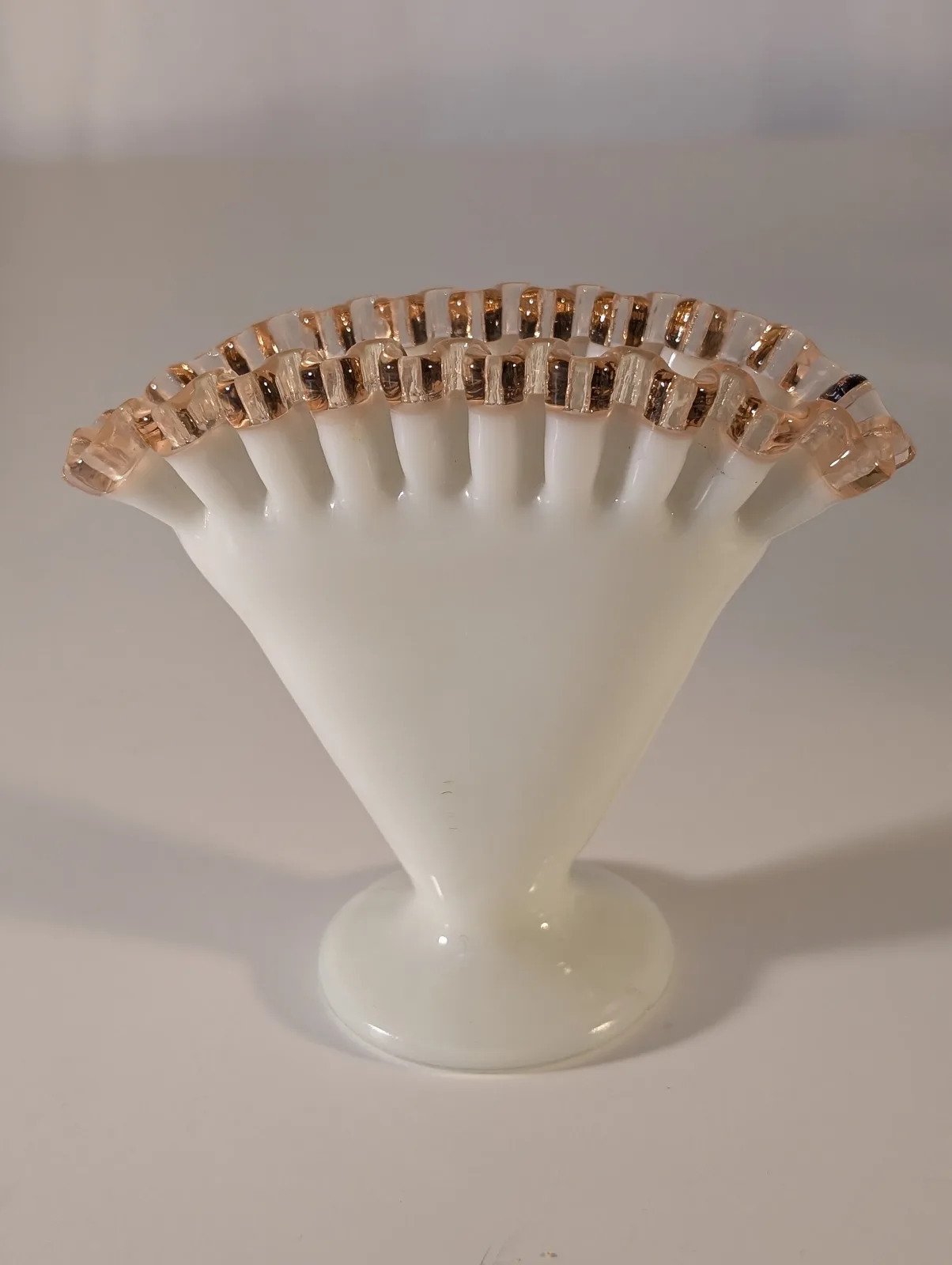 Milk-glass fan vase with vertical ribs opening into a wide fan, its closely crimped rim in pale pink