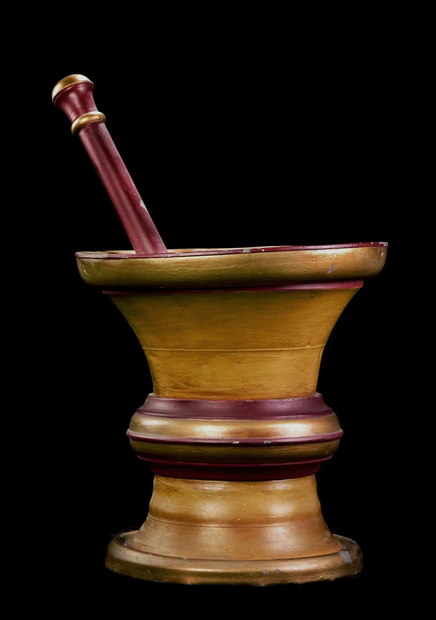 Large turned wooden mortar and pestle painted gold with deep red bands, used as an apothecary's shop sign