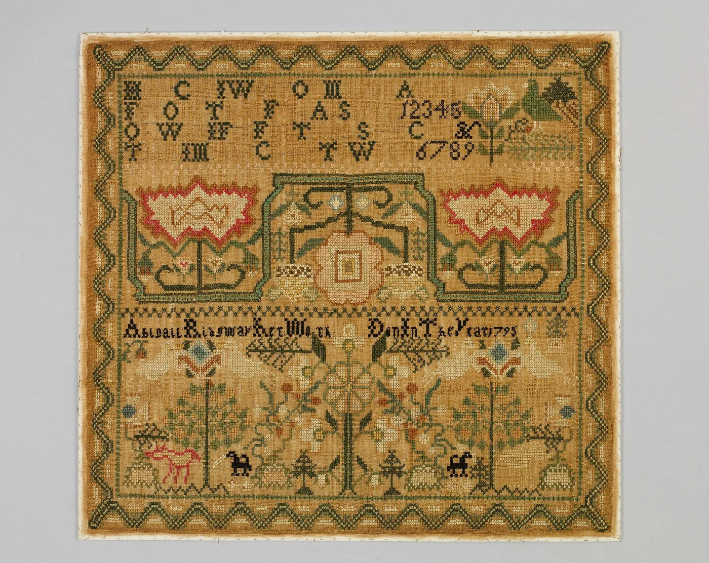 Sampler of 1795 on a browned linen ground with green zigzag borders, paired red and cream carnations, a flowering vine and small animals