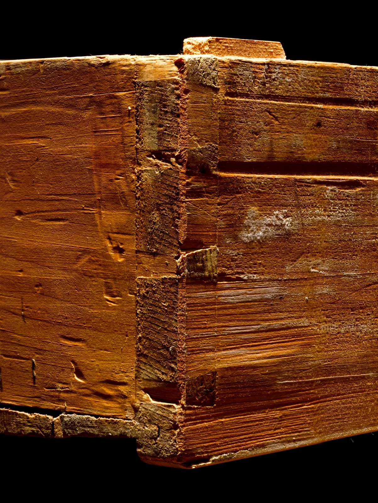 Close-up of the corner of an old drawer, with a few wide hand-cut dovetails, saw and chisel marks and plane tracks across the boards
