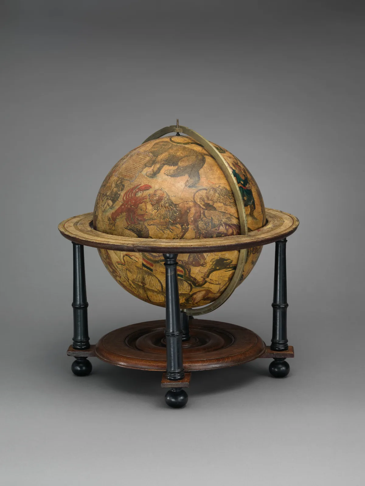 Globe printed with constellation figures and star positions, mounted in a brass meridian ring on a turned wooden stand with a broad horizon circle and four legs