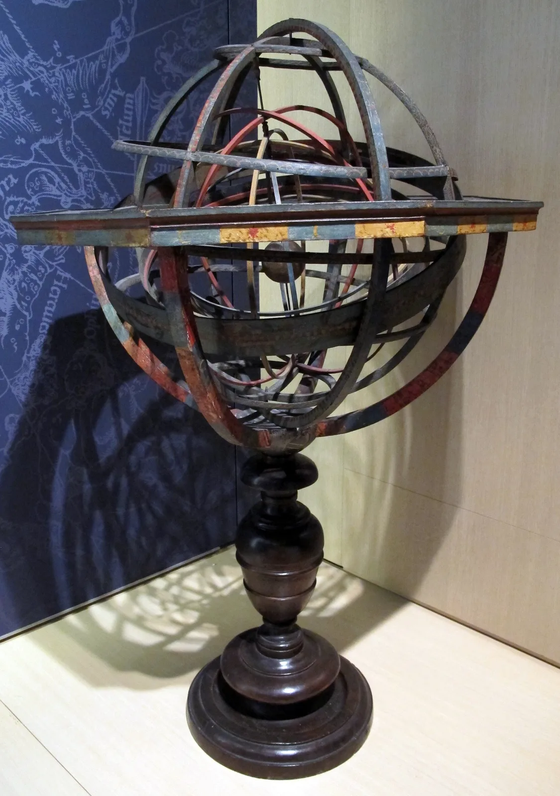 Armillary sphere of concentric brass and painted rings representing the celestial circles, with a small earth at the centre, mounted on a turned wooden baluster stand