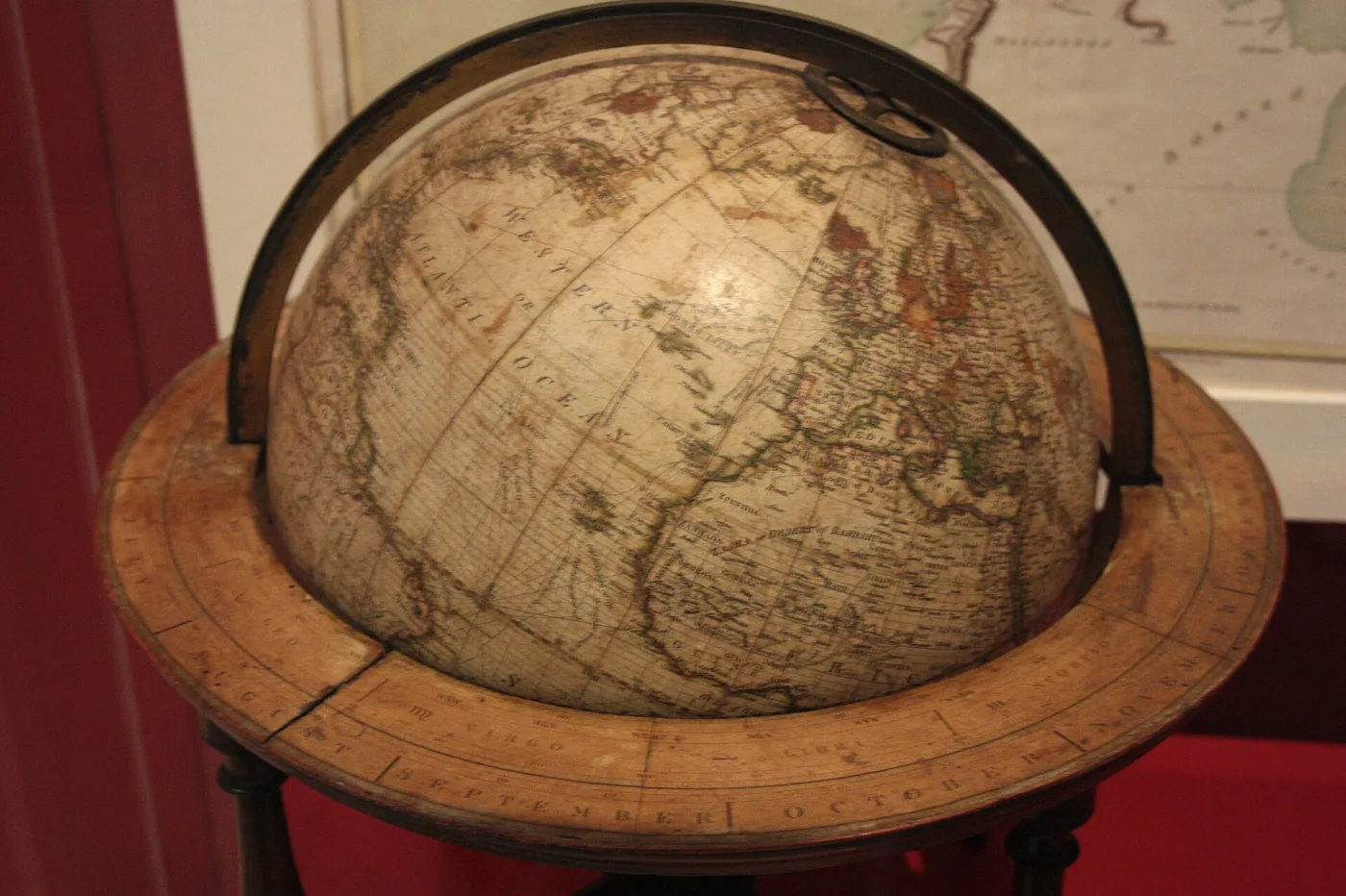 Large terrestrial globe seen close up, the printed map surface showing fine vertical seams where the tapering paper segments meet, set within a broad flat wooden horizon ring