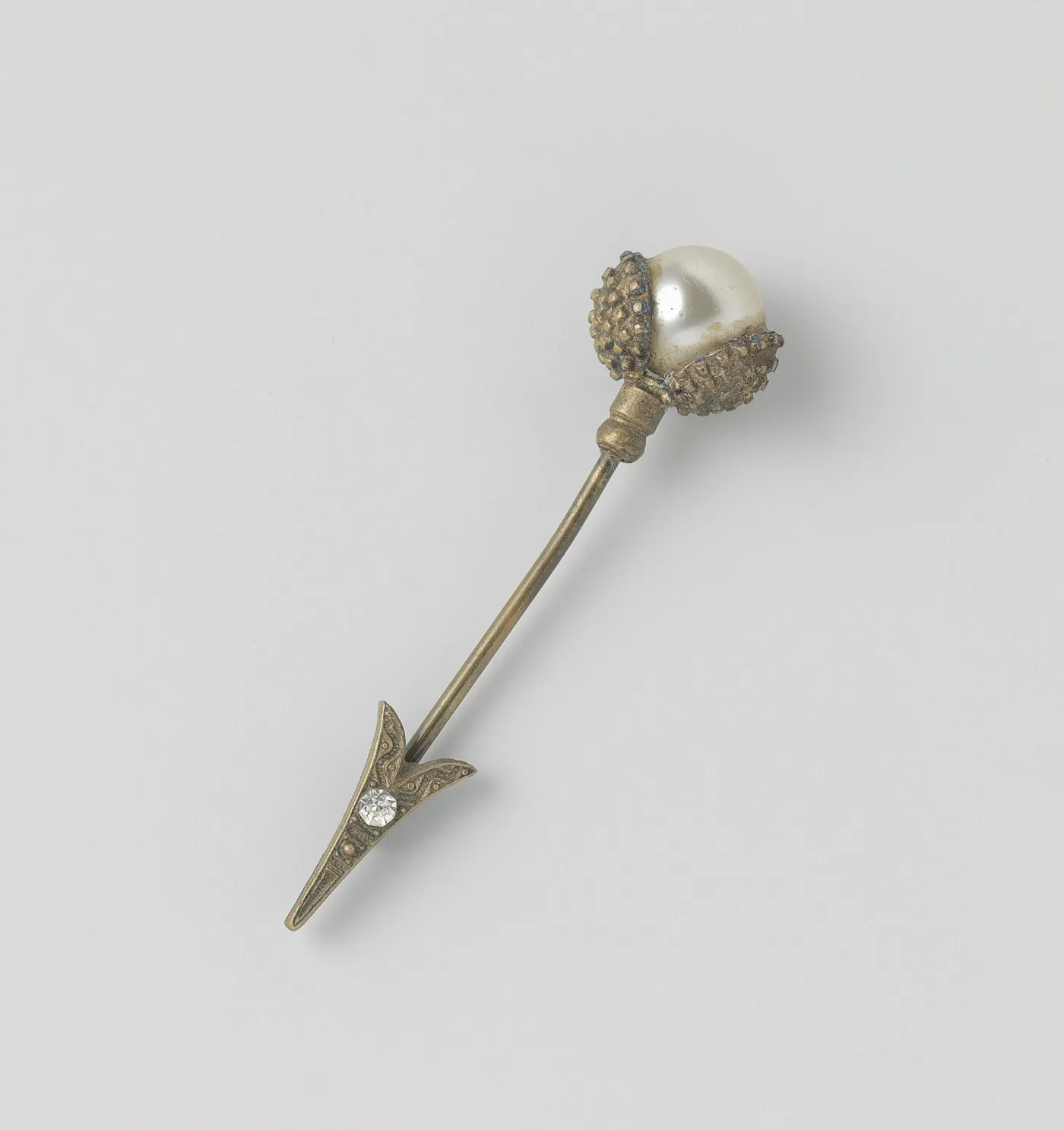 Hat pin with a pearl head in a granulated cap, and a separate arrow-shaped protector set with a clear stone slipped over the shaft to sheathe the point