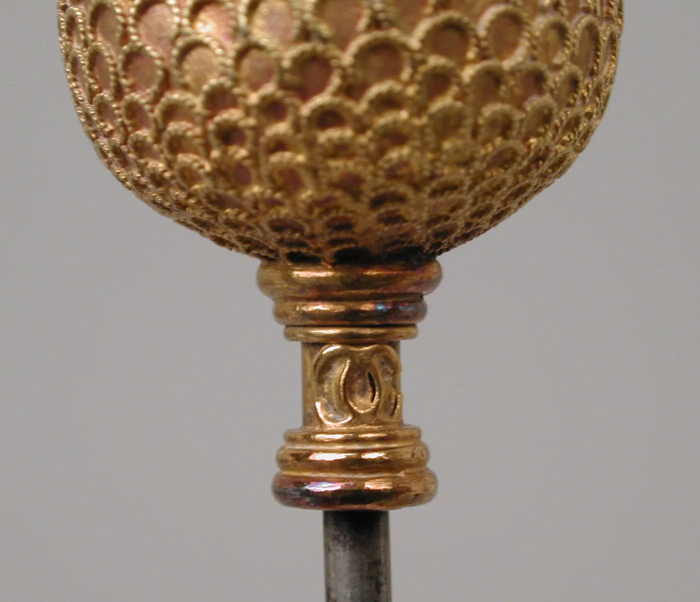Close-up of the gold collar below the head, showing two interlocking letter C's back to back