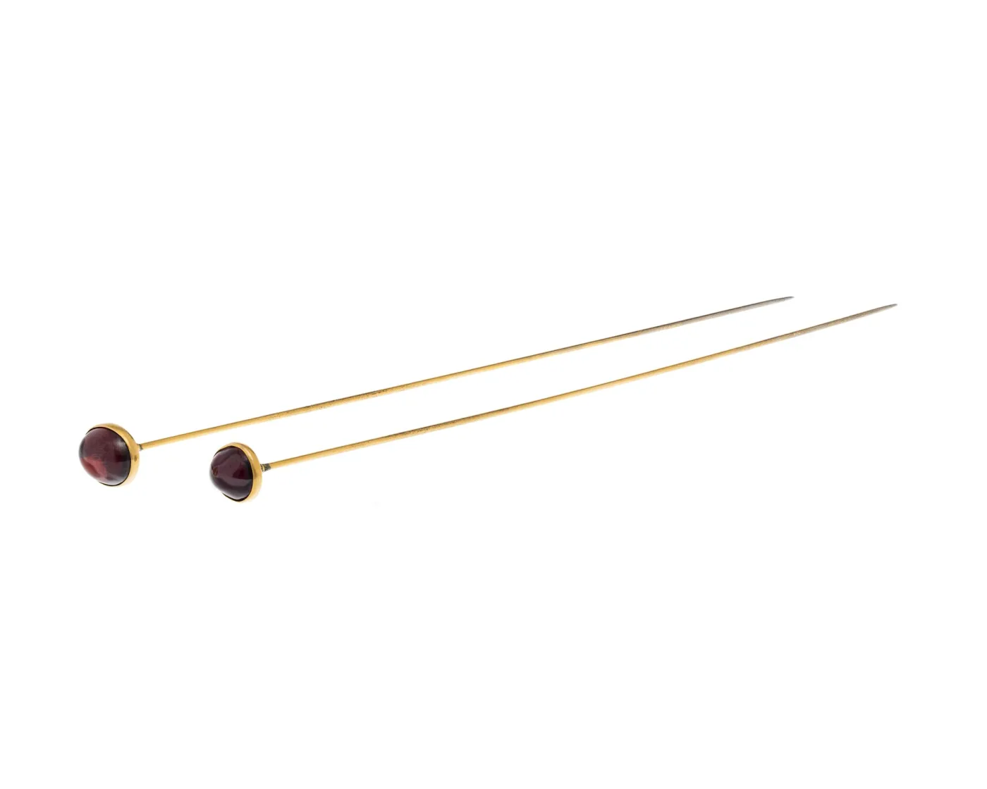 Two hat pins with round dark red cabochon stones in plain gold collets, on gilded shafts