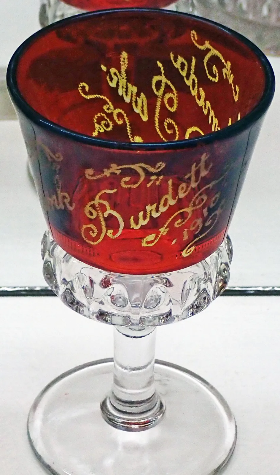 Pressed glass wine glass with a clear stem and a ruby-stained bowl lettered in gold with a personal name