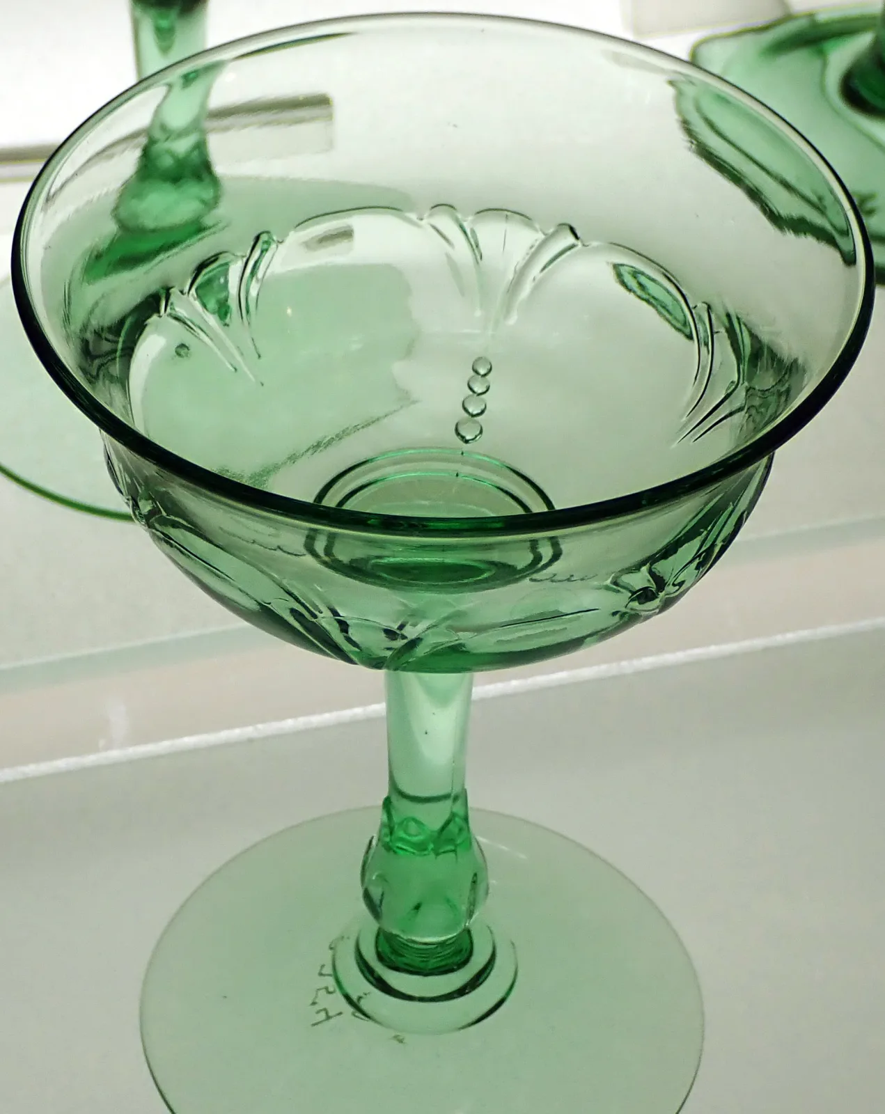 All-green pressed champagne glass with a shallow bowl moulded with fan motifs, on a short stem and round foot